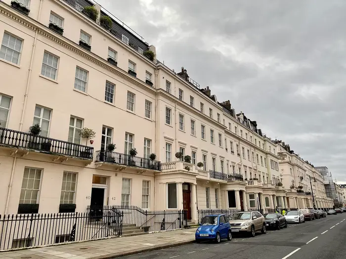A long cream stucco terrace with black railings on Eaton Place, Belgravia