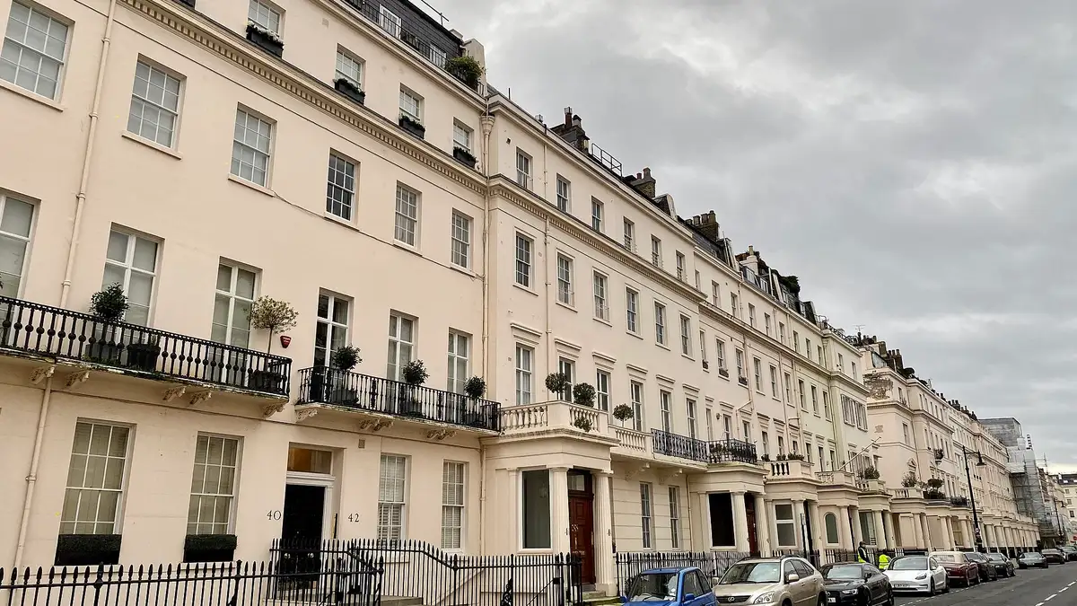 A long cream stucco terrace with black railings on Eaton Place, Belgravia